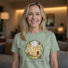 A woman wearing a sage green t-shirt with a travel-themed coffee graphic and passport slogan.