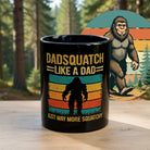 Black ceramic mug with a retro Dadsquatch design and a cartoon Bigfoot illustration.