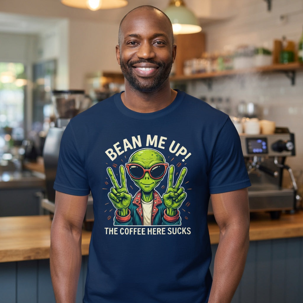 A man wears a navy blue t-shirt with a cartoon alien and the text Bean Me Up! The Coffee Here Sucks.