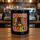 Black ceramic mug featuring a colorful psychedelic illustration and the text Decaf Is a Joke.