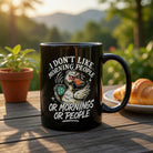 Black ceramic mug with a grumpy duck and the text I don't like morning people or mornings or people.