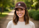 Brown corduroy baseball cap featuring an embroidered white coffee cup logo with a heart.