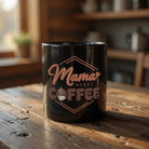 Black ceramic mug with Mama Needs Coffee graphic on a rustic wooden table.