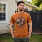 A man wearing a rust-colored t-shirt with a vintage western rooster coffee graphic.