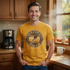 A man wearing a mustard yellow t-shirt with a vintage-style graphic of a coffee bean sperm cell.