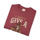 Folded maroon t-shirt featuring a graphic of a rat in a cowboy hat riding a donkey.
