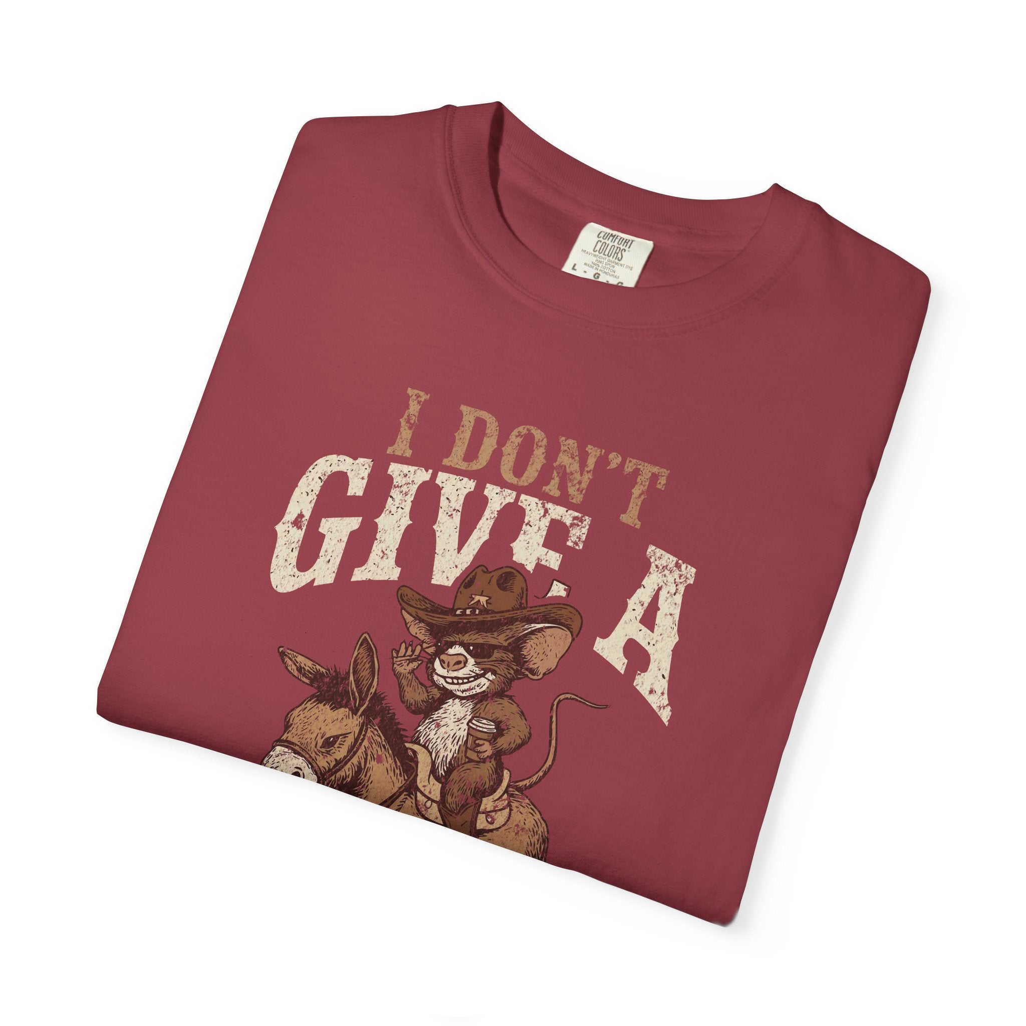Folded maroon t-shirt featuring a graphic of a rat in a cowboy hat riding a donkey.