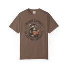 Brown unisex t-shirt featuring a raccoon wearing sunglasses and reading a book with coffee.