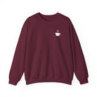 A maroon crewneck sweatshirt featuring a small white steaming coffee cup icon on the chest.
