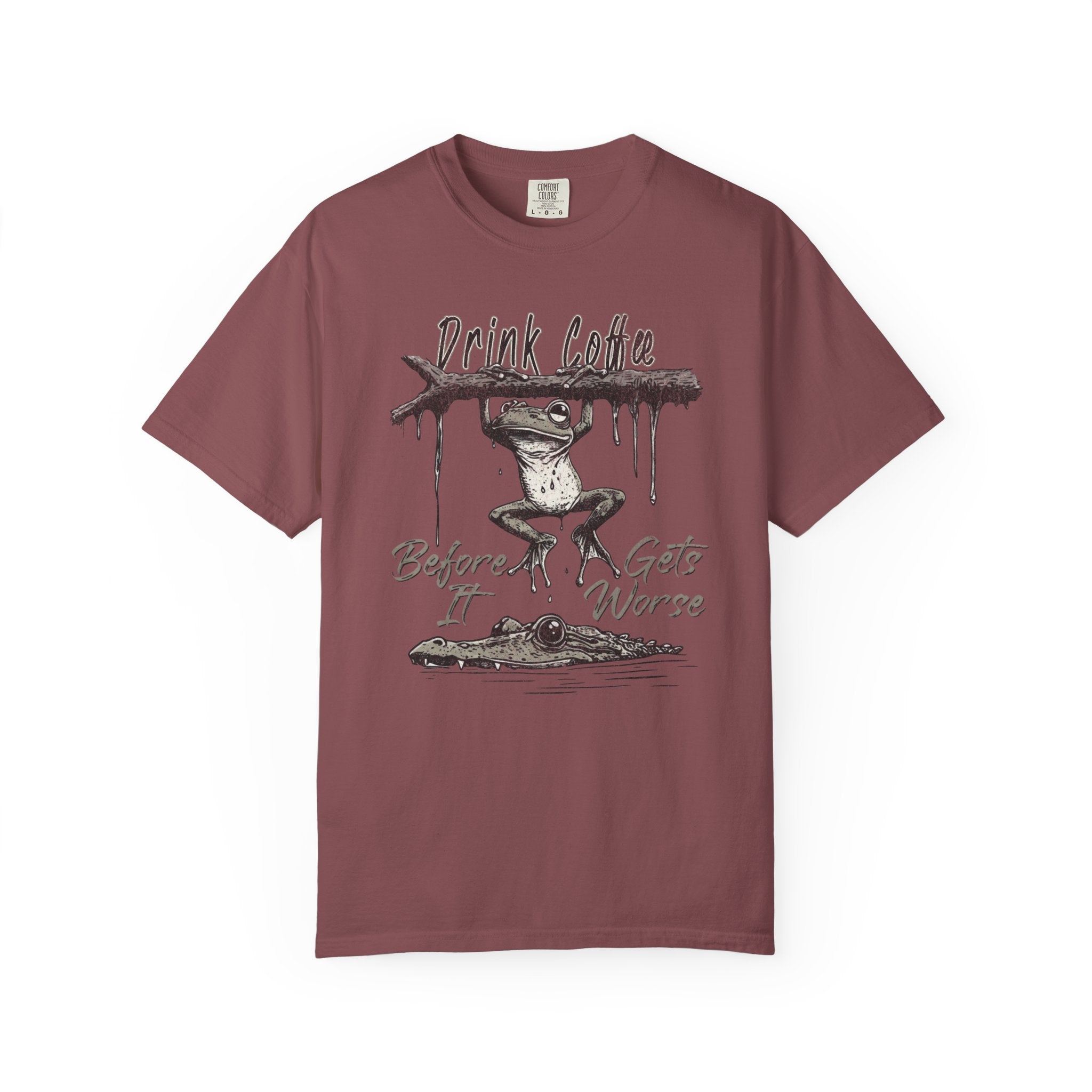 A maroon unisex t-shirt featuring a graphic of a frog hanging from a branch above an alligator.