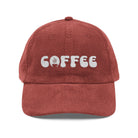 A rust-colored corduroy dad hat with the word COFFEE embroidered in white on the front.