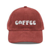 A rust-colored corduroy dad hat with the word COFFEE embroidered in white on the front.