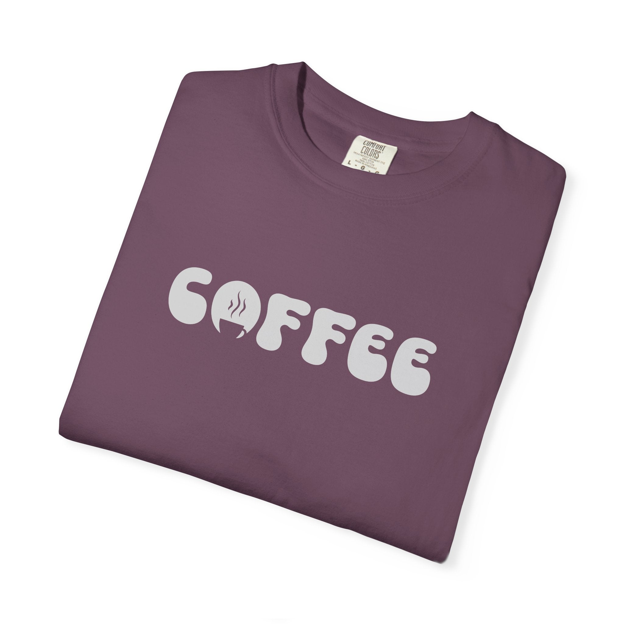 A folded plum-colored cotton t-shirt featuring the word COFFEE in a white retro bubble font.