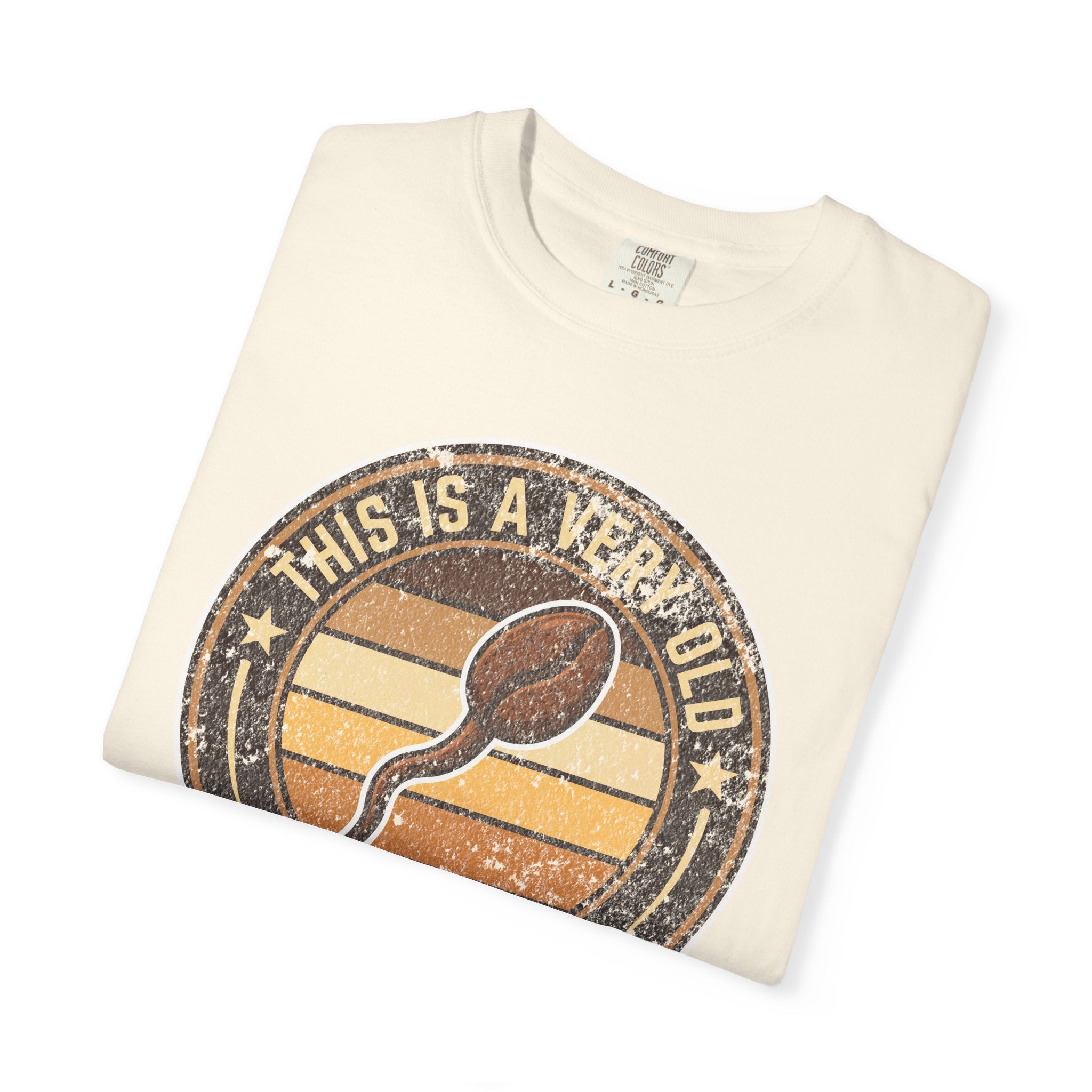 Folded cream-colored t-shirt with a vintage-style graphic of a coffee bean and text.