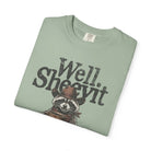 Sage green t-shirt featuring a distressed graphic of a raccoon in a cowboy hat holding coffee.