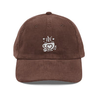 Brown corduroy baseball cap with an embroidered white coffee cup logo featuring a heart design.