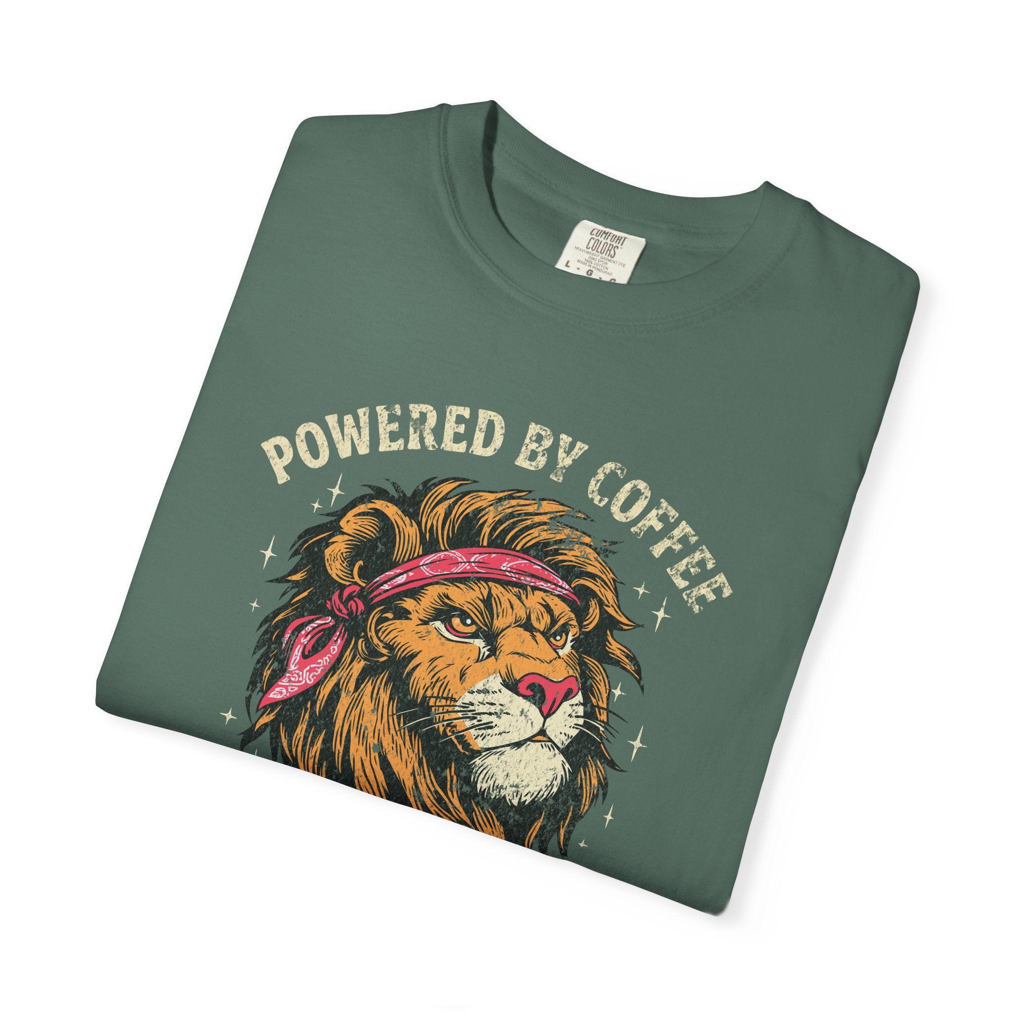 Folded green t-shirt featuring a graphic of a lion wearing a bandana with Powered by Coffee text.