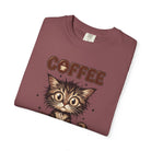A folded maroon unisex cotton t-shirt featuring a graphic of a wide-eyed kitten and the word COFFEE.