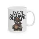 White ceramic mug featuring a graphic of a cowboy raccoon holding a coffee cup.