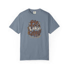A blue short-sleeved t-shirt featuring a distressed retro graphic that says Be Like Coffee.