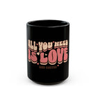 Black ceramic mug with retro 70s style text reading All You Need Is Love And Coffee.