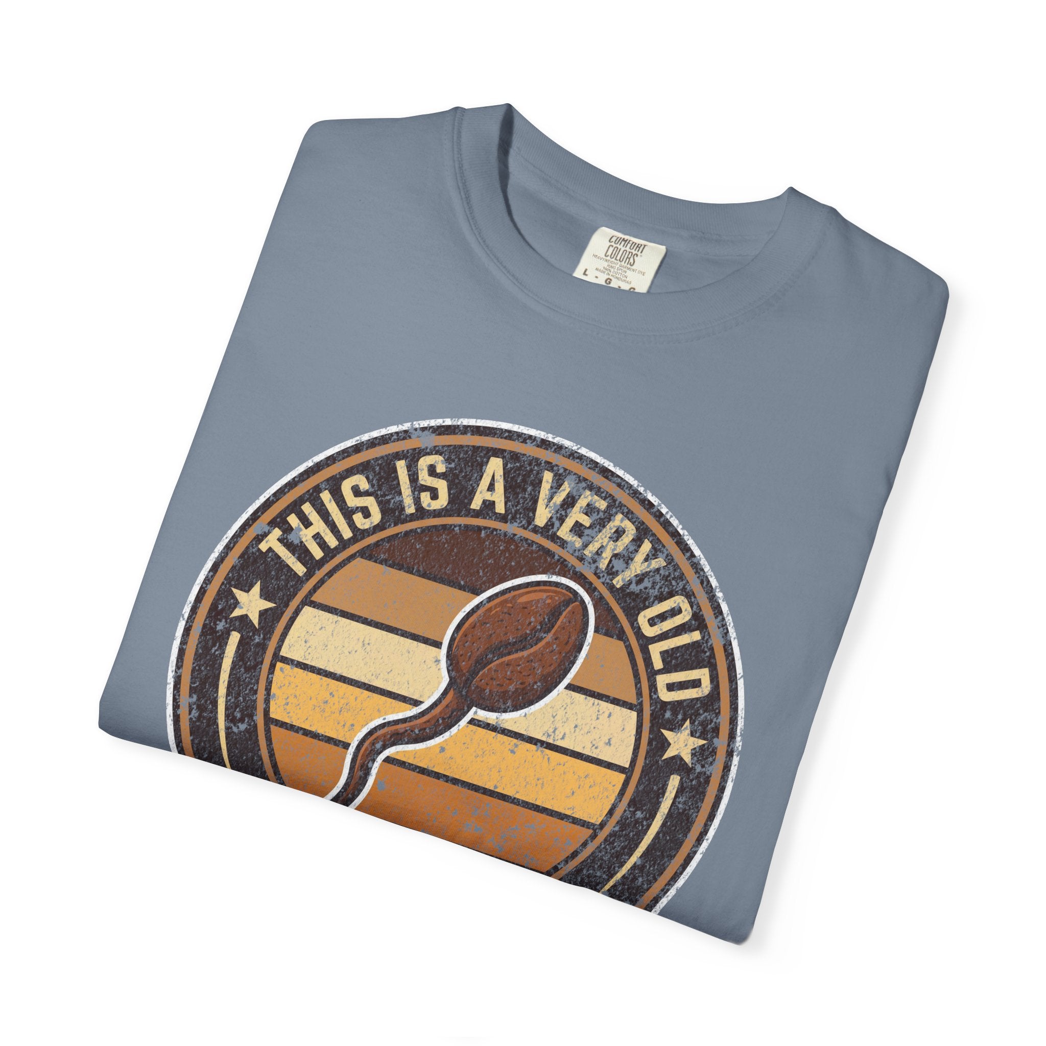 Folded blue t-shirt with a vintage-style graphic of a coffee bean and text.