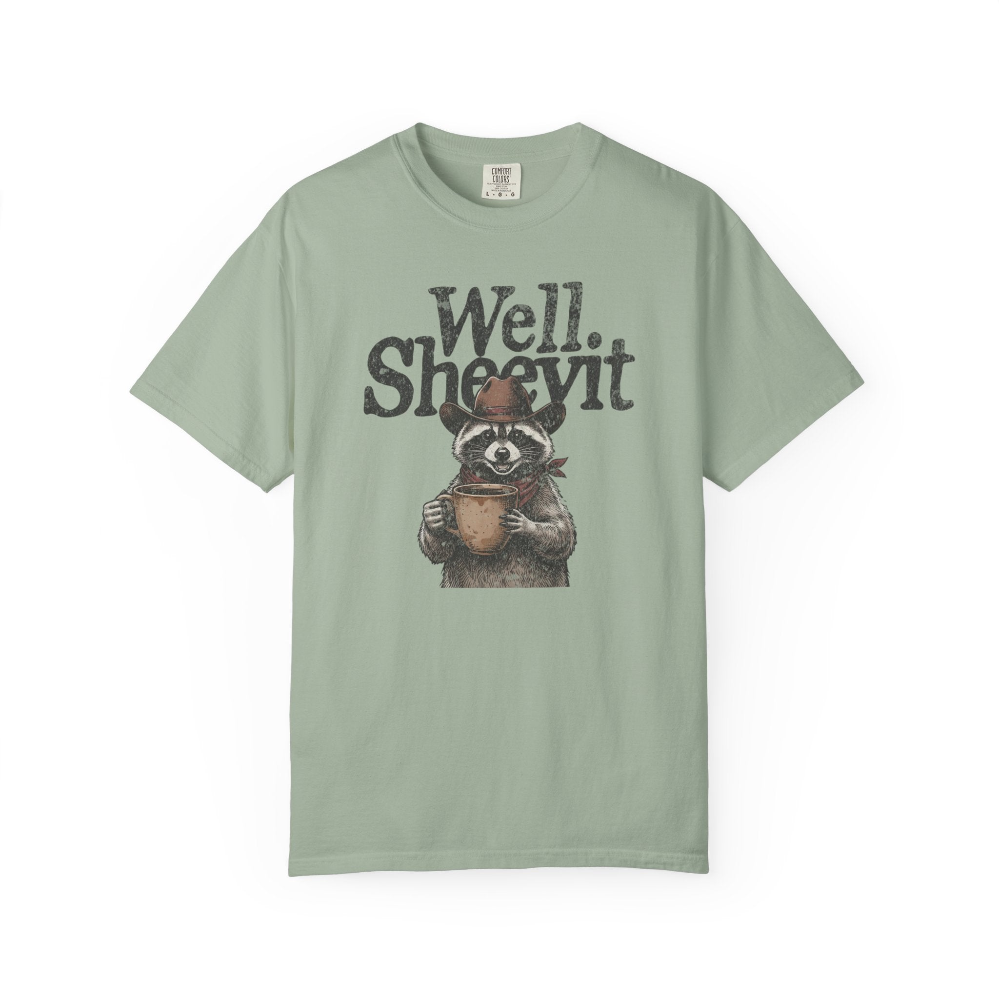 Sage green t-shirt featuring a graphic of a raccoon in a cowboy hat holding a coffee mug.