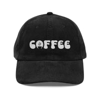 A black corduroy dad hat with the word COFFEE embroidered in white on the front.