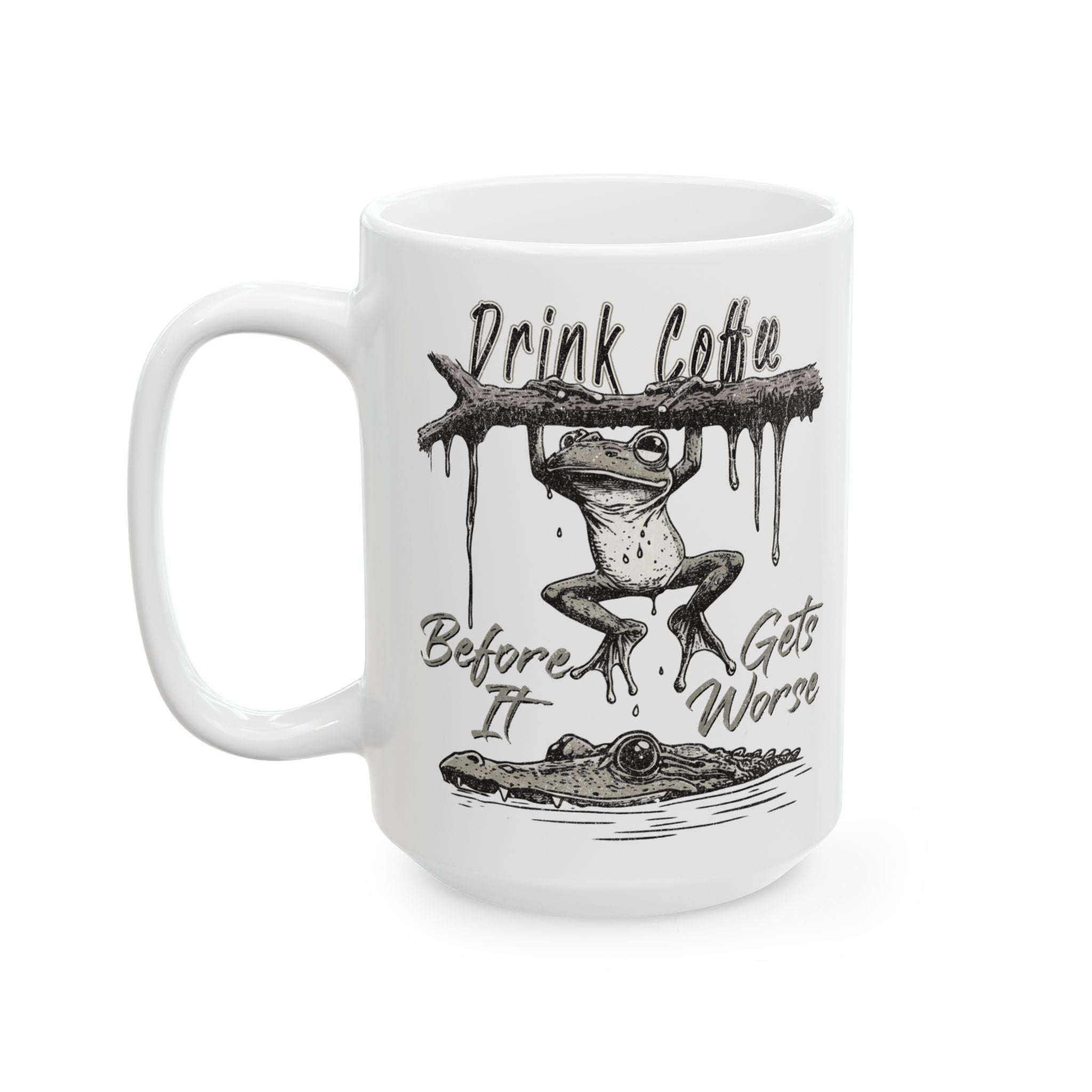 White ceramic coffee mug featuring a frog hanging from a branch above a lurking alligator.