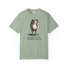 A sage green cotton t-shirt featuring a graphic of a frog holding a coffee mug with text below.