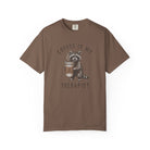Brown unisex cotton t-shirt featuring a distressed graphic of a raccoon holding a coffee cup.