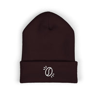 A dark brown cuffed knit beanie featuring a small white embroidered coffee bean graphic.