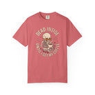 A coral-colored t-shirt featuring a skeleton wearing sunglasses and holding a coffee mug.