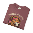 Folded maroon t-shirt featuring a graphic of a lion wearing a bandana with Powered by Coffee text.