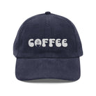 A navy blue corduroy dad hat featuring the word coffee embroidered in white on the front.