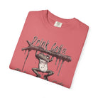 A folded coral-colored unisex t-shirt featuring a graphic of a frog hanging from a branch.