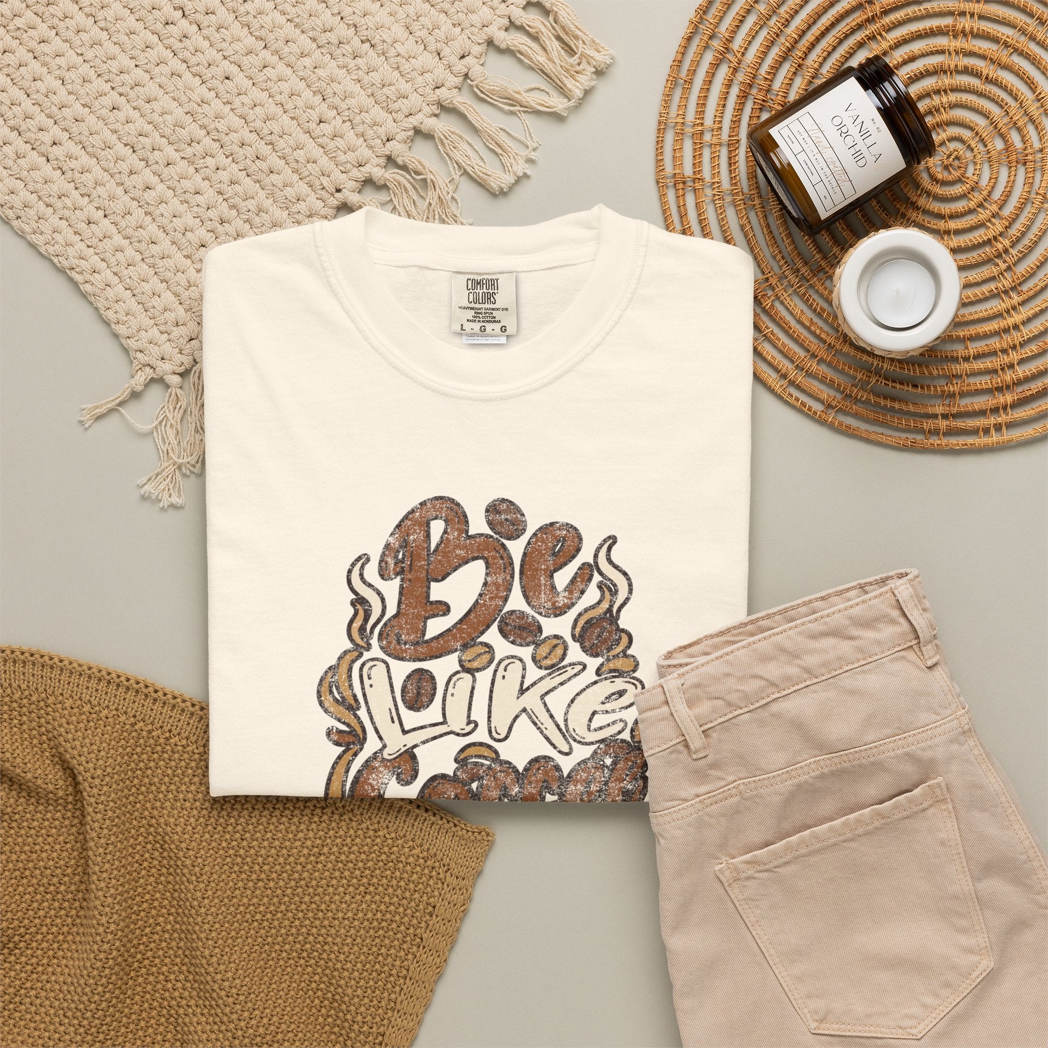 An ivory Comfort Colors t-shirt with a retro distressed coffee-themed graphic on a flat lay.