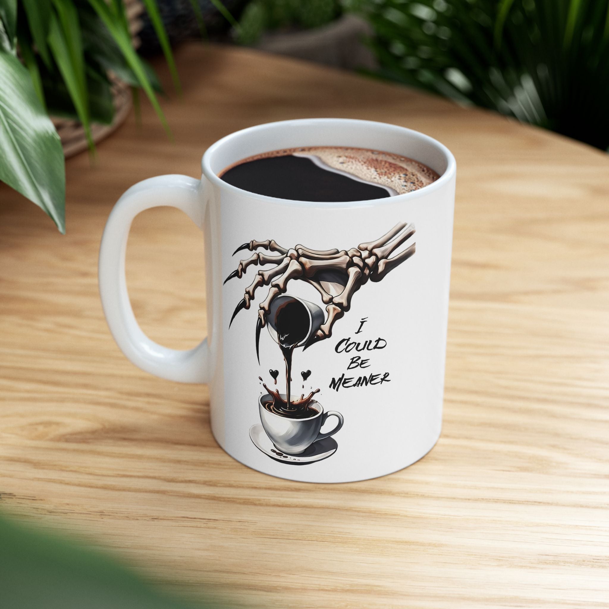A white coffee mug with a skeleton hand pouring coffee and the text "I Could Be Meaner".