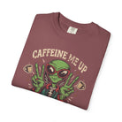 A folded maroon unisex cotton t-shirt featuring a distressed graphic of an alien making peace signs.