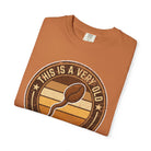 Folded orange t-shirt with a distressed graphic of a coffee bean and text This Is A Very Old.