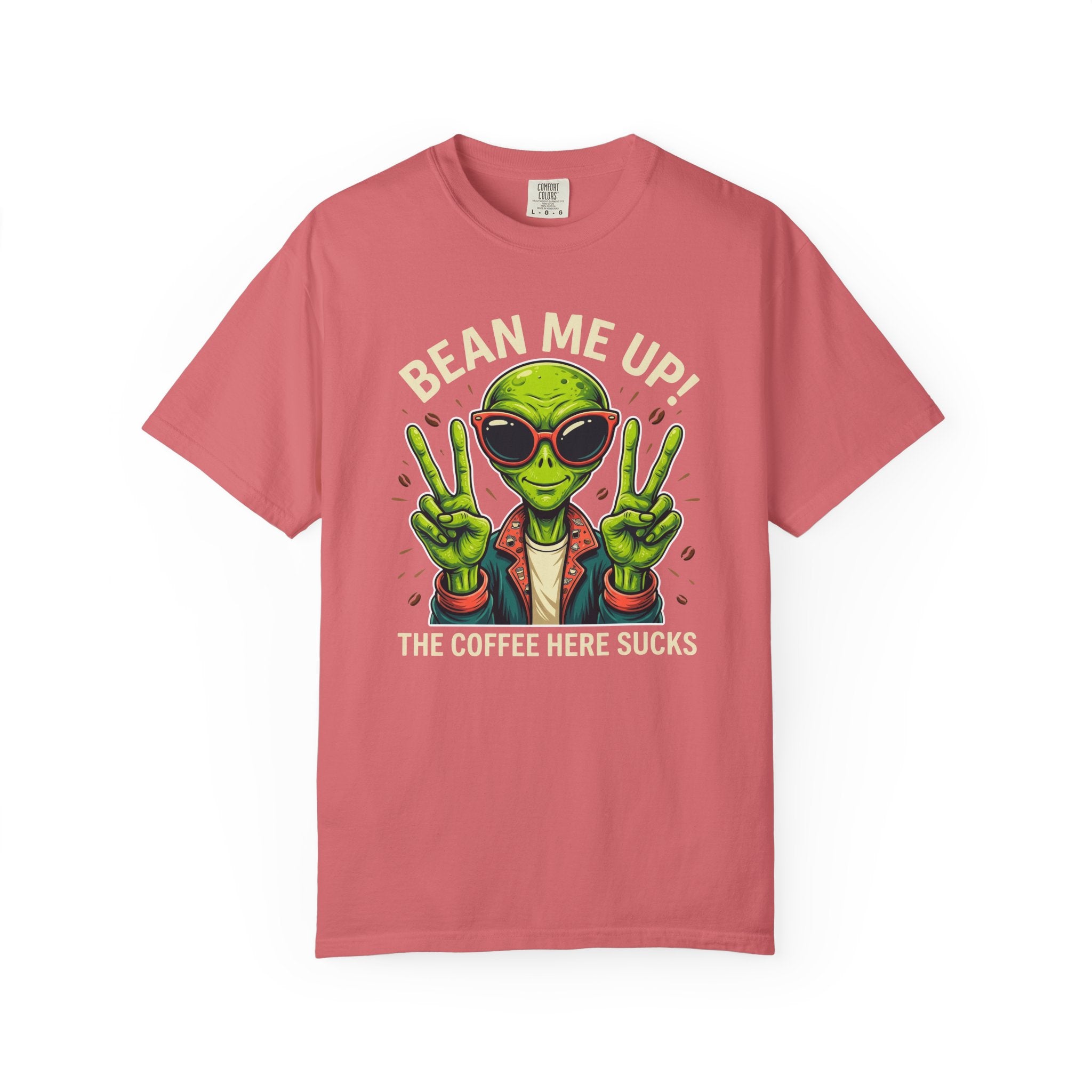 A coral-colored t-shirt featuring a green alien wearing sunglasses and making peace signs.
