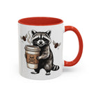 White ceramic mug with a red handle and interior, featuring a raccoon holding a coffee cup.