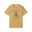 Mustard yellow unisex cotton t-shirt featuring a raccoon holding a coffee cup with a skull logo.